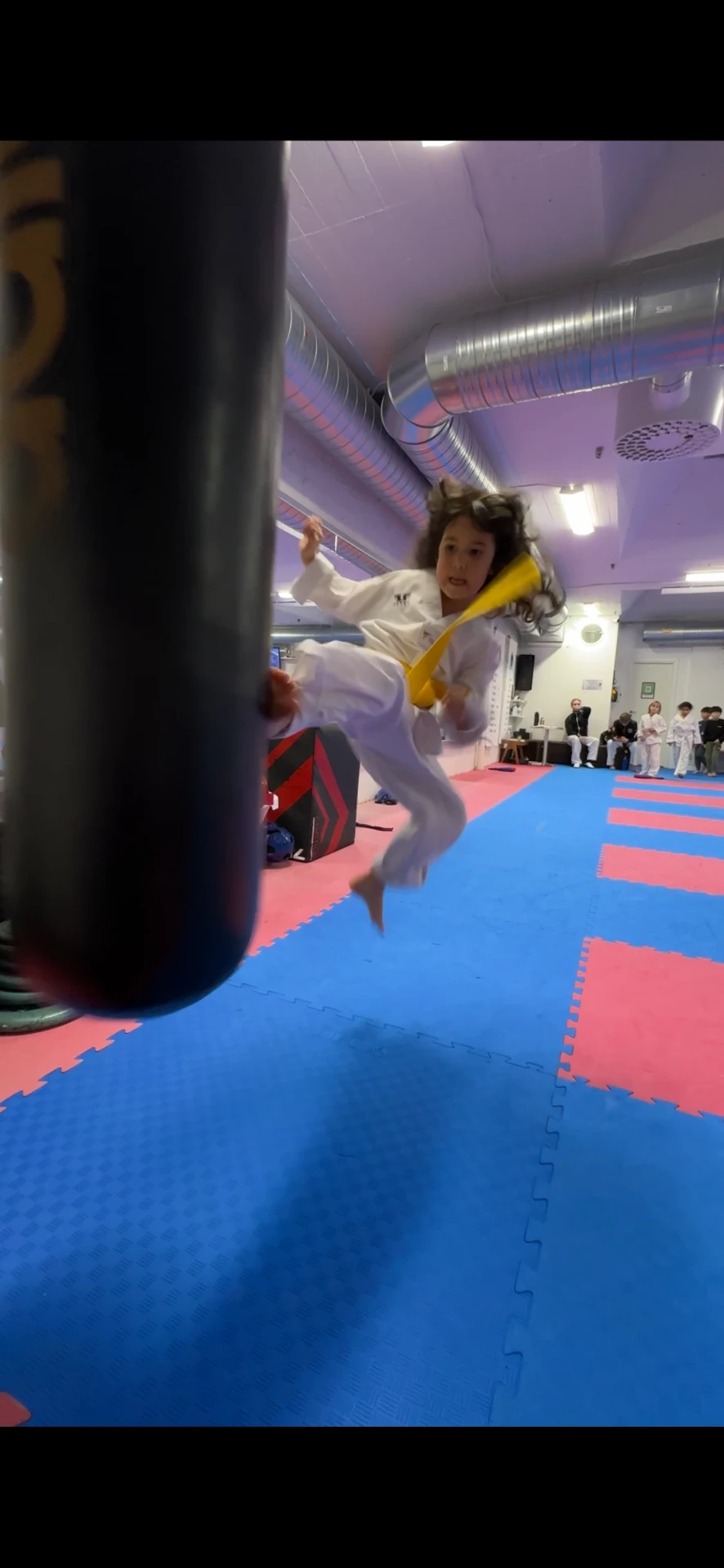 Flicka tränar sparkteknik mot säck under Taekwondopass